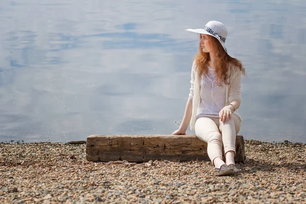 红头发的年轻女人独自坐在岸边在炎热的夏天. — 图库照片