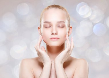 Güzel genç kadın temiz taze cilt ile kendi yüz dokun. Fac