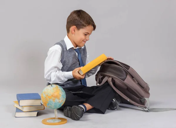 Ung pojke sätter böckerna i sin ryggsäck. — Stockfoto