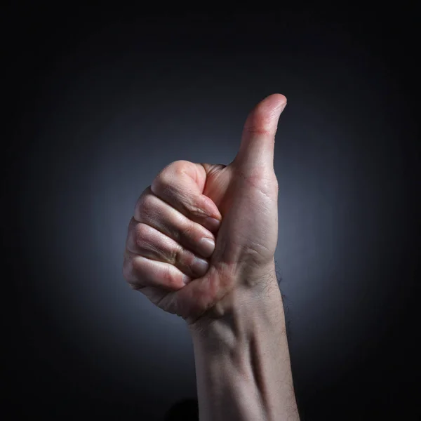 暗い背景に親指を立ててクローズ アップと承認のジェスチャーで人間の手 — ストック写真