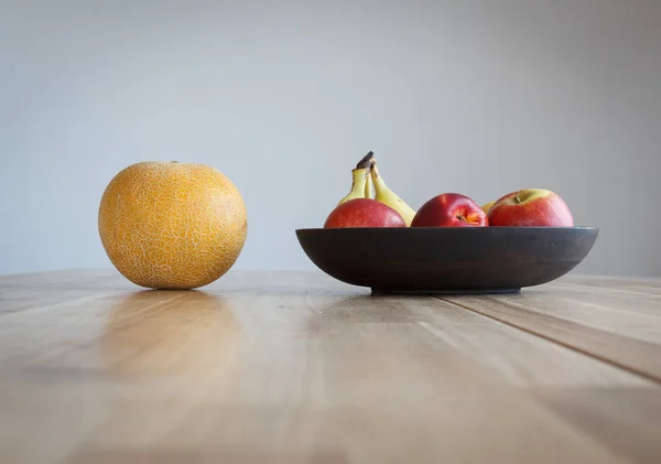 Στρογγυλό Κίτρινο Πεπόνι Και Άλλα Φρούτα Ένα Ξύλινο Τραπέζι — Φωτογραφία Αρχείου
