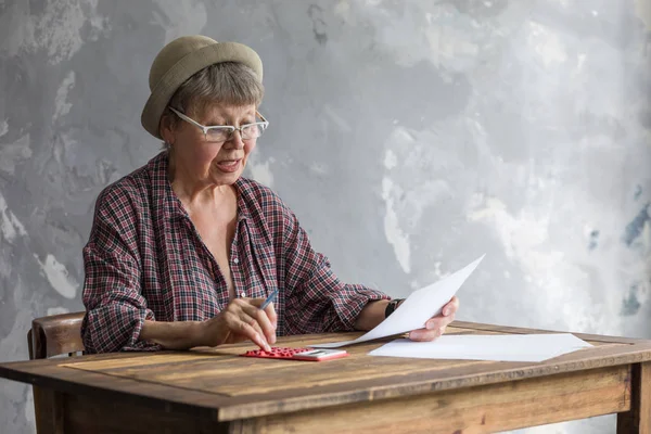 Een Oudere Vrouw Met Een Rekenmachine Betaaldocumenten Zittend Aan Een — Stockfoto