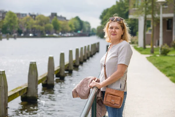 一位快乐的老妇人站在城市的运河岸边 享受夏天的一天 老年人积极生活方式的概念 — 图库照片