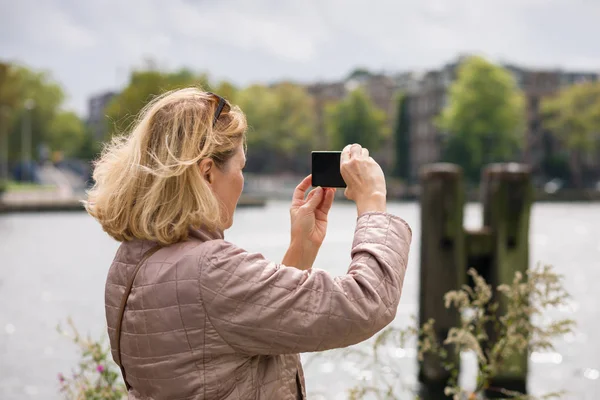 Egy Idős Mobiltelefonnal Fotózza Város Látnivalóit Végigsétálva Nyári Város Utcáin Stock Kép