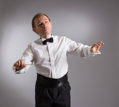 Orkestra şefinin portresi. Hafif bir arkaplanda duygusal olarak el kol hareketi yapıyor..