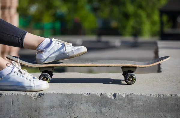 Skateboard and women\'s feet on the background of city streets.
