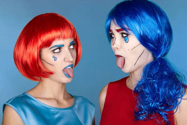 Females in red and blue wigs on blue background. Girls show each