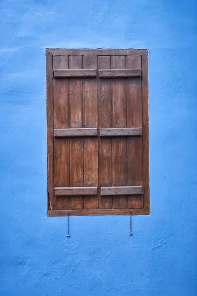 The view of the window with the wooden brown shutter in the wall which is  painted blue  a common color in Cyprus. Pano Lefkara village. Cyprus