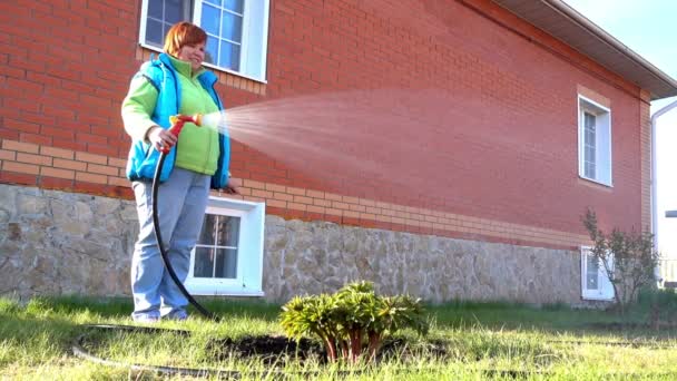 Woman watering a flower garden — Stockvideo