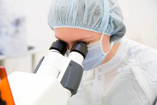 Женщина-исследователь смотрит в микроскоп — стоковое фото