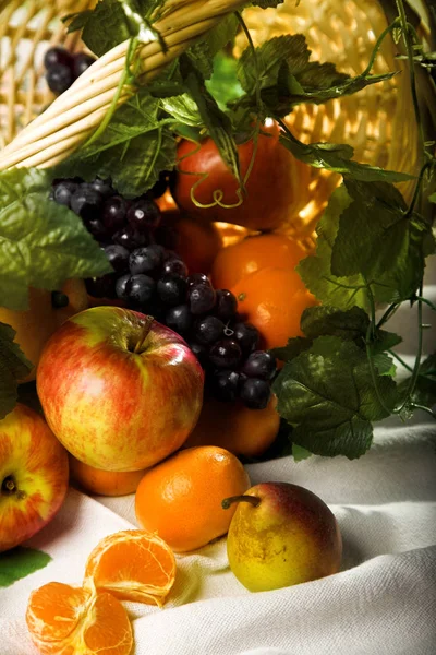 Fruktkorg och gröna blad — Stockfoto
