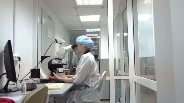 Woman researcher looking in microscope — Stock Video
