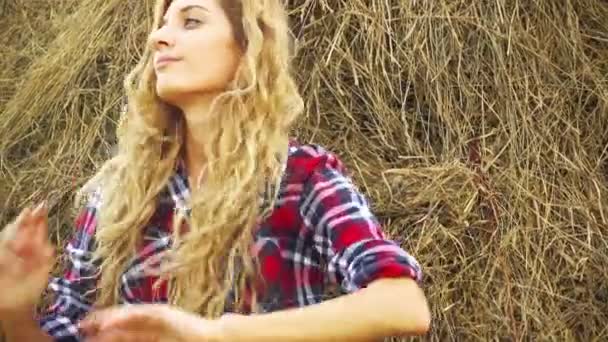 Молодая женщина отдыхает на стоге сена — стоковое видео