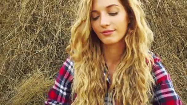 Молодая женщина отдыхает на стоге сена — стоковое видео