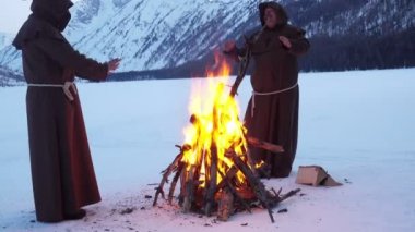 Rahipler kış dağlarda kamp ateşi etrafında Isınma