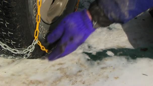 Hombre poniendo cadenas de nieve en el neumático — Vídeo de stock