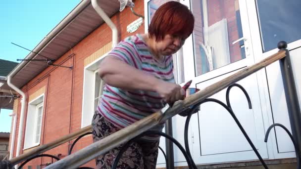 Женщина лакирует деревянные перила — стоковое видео