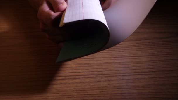 空白のノートブックを開くと 木製のテーブルの上を保持しているページをめくる手します — ストック動画