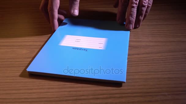 空白のノートブックを開くと 木製のテーブルの上を保持しているページをめくる手します — ストック動画