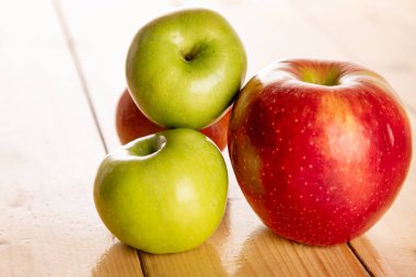 Ahşap masada kırmızı ve yeşil elmalar