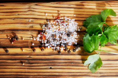 Ahşap bir masada yeşil kereviz, tuz ve biber yaprakları.