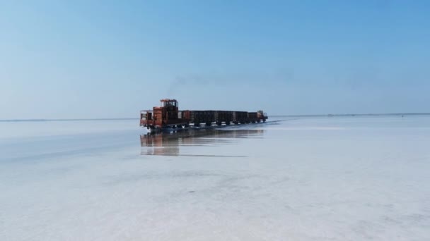 塩湖を通って水の中に敷設された鉄道に古い列車に乗る 列車は水から移動します ブルリン湖で塩を採掘 アルタイ ブルソル ロシアだ 2019年8月 — ストック動画
