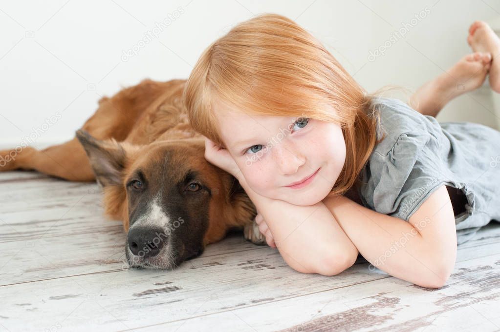 Red-haired girl and red-haired dog lie on the floor