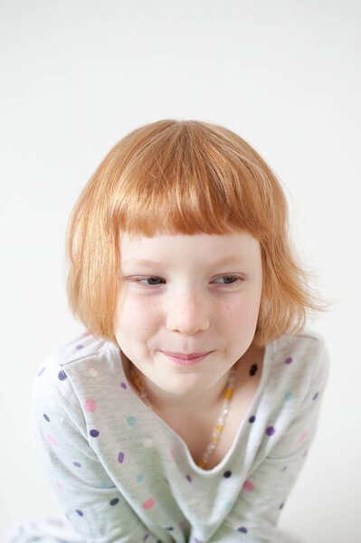 Симпатичная рыжая девушка хитро улыбается.
