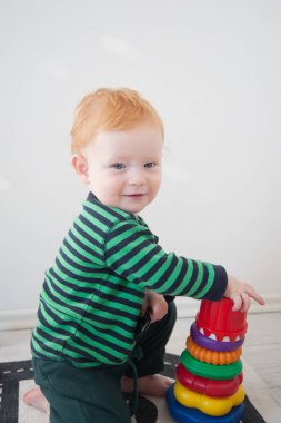 Kırmızı çocuk beyaz zemin üzerine bir piramit ile oynarken