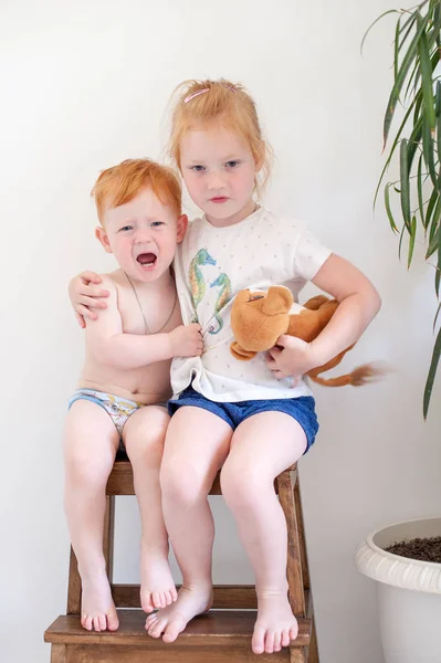 Red-haired brother and sister in one chair