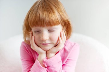 Bir kız bir kary saç modeli ile kapalı gözleriyle oturur