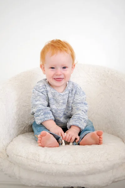 Jongen Spijkerbroek Zit Een Witte Fauteuil — Stockfoto