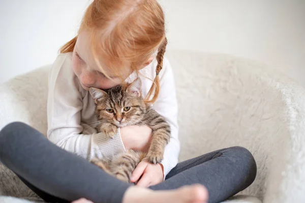 Girl hugging a kitten on the sofa