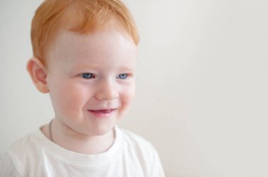 Kızıl saçlı çocuk beyaz arka plan üzerinde gülümseyen