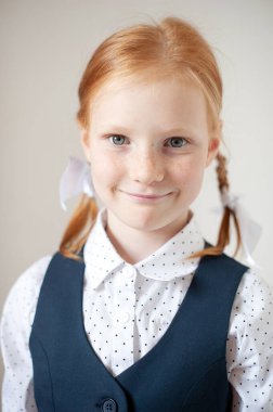 Beyaz arka planda gülümseyen kızıl saçlı okul kızı.