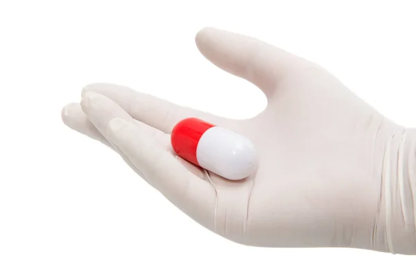 Mão segurando uma cápsula ou pílula em luvas médicas — Fotografia de Stock