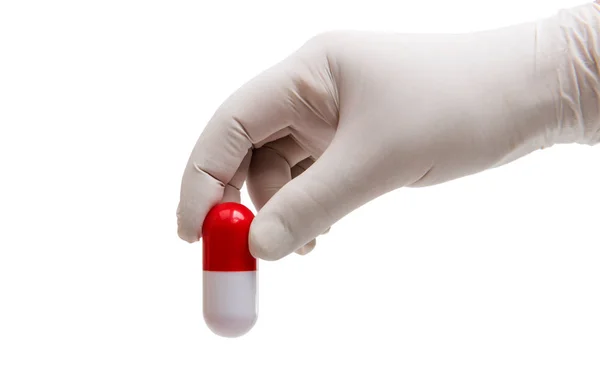 Hand holding a capsule or pill in medical gloves — Stock Photo, Image