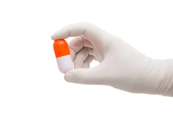 Hand met een capsule of pil in medische handschoenen — Stockfoto