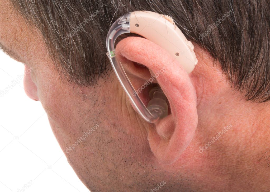 A modern hearing aid on the ear of a young European guy. 