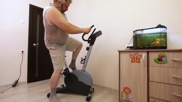 Mann auf Heimtrainer in Zimmer verwickelt — Stockvideo