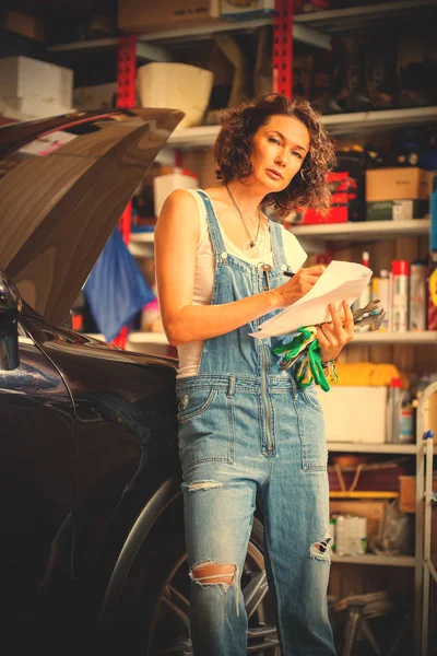 beautiful woman mechanic in blue overalls makes recording