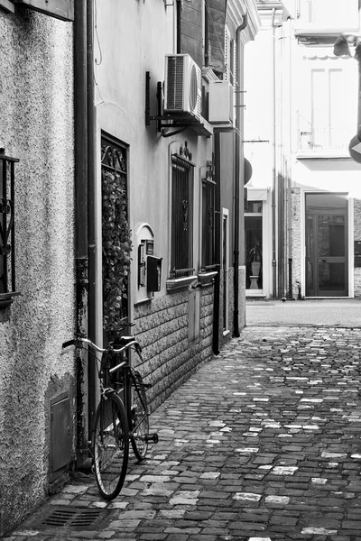 Street and bicycle near wall in Rimini, Italy. Italian black and white cityscape