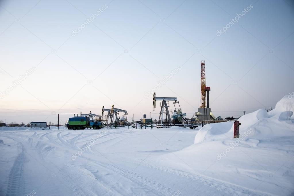 Oil field. Drilling rig and oil pump.