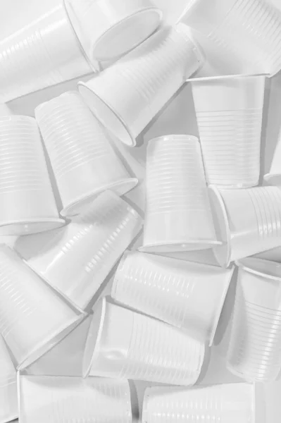 Одноразовые пластиковые чашки на белом фоне. Минималистичный экологически чистый натюрморт. Концепция проблемы "зеленых" технологий и экологии . — стоковое фото
