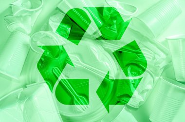 Yeşil arkaplanda tek kullanımlık plastik sofra takımı ve geri dönüşüm tabelası. Ekolojik olarak temiz, minimalist bir hayat. Pop Art. Ve ekoloji problemi kavramı.