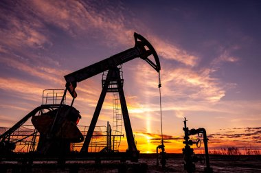 Arka planda gün batımına karşı Petrol Pompası. Endüstriyel Güç üretimi için sallanan makineler. Petrol ihracı. Petrol fiyatlarıyla savaş. Küresel Coronavirüs COVID 19 krizi.
