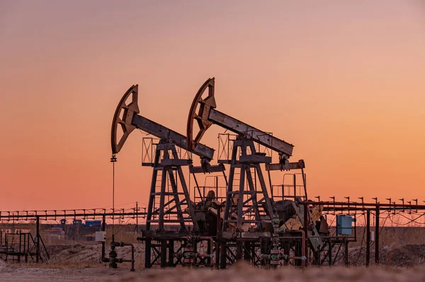 Oil pump rig. Oil and gas production. Oilfield site. Pump Jack are running. Drilling derricks for fossil fuels output and crude oil production. War on oil prices. Global coronavirus COVID 19 crisis. — Stock Photo, Image