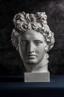 Apollo 'nun eski Güneş Tanrısı heykelinin beyaz alçıtaşı kopyası koyu dokulu arka planda sanatçılar için. Rönesans dönemi. İnsan yüzünün alçı heykeli.