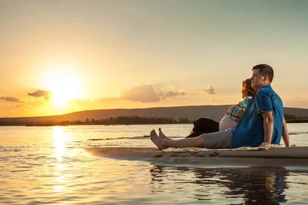 Schönes Paar sitzt am Strand und schaut die Sonnen an — Stockfoto