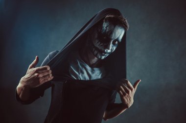 Ürkütücü yüzü ile kapüşonlu adam zombi.